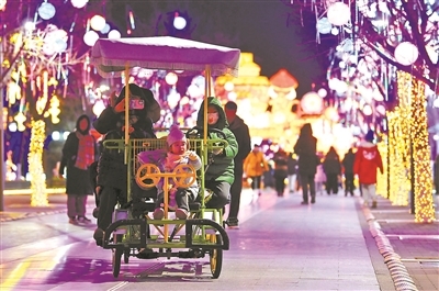游客在北京世园边骑车边赏灯 摄影/本报记者 袁艺