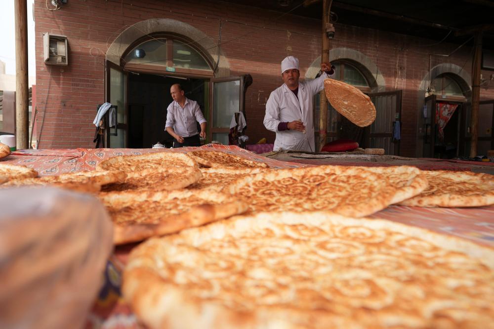 9月19日,达西村村民肉则·赛麦提(右)在文旅商业街上制作馕。近年来,达西村打造文旅商业街,吸引村民入驻,为村民增收。