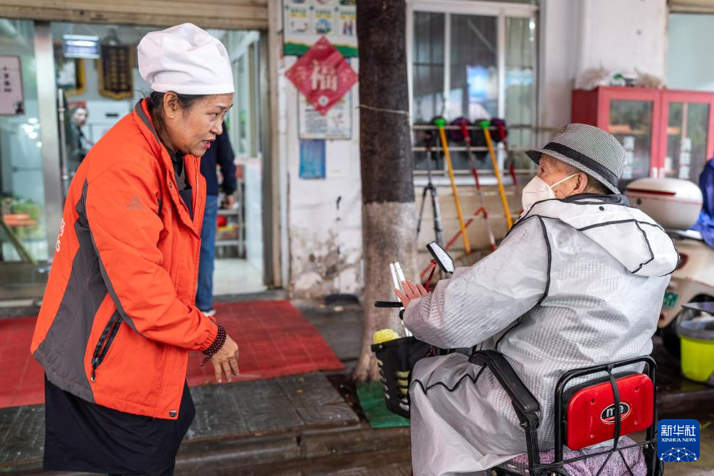 在昆明市幸福家园小区爱心食堂,王兰兰(左)与一名老人交谈(5月28日摄)。