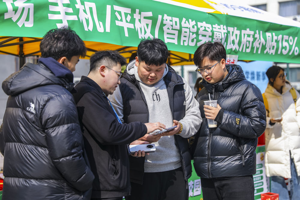 2025年3月6日,学生在山东省青岛恒星科技学院开展的消费品以旧换新活动中选购手机。(张鹰 摄)