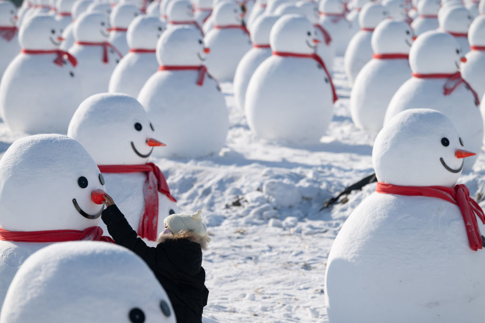 ↑1月4日，在北大荒集团闫家岗农场，游客在雪人群中游览。新华社记者 张涛 摄