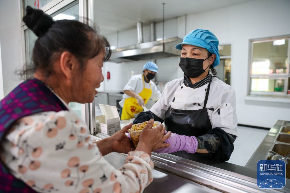 ↑ 8月9日，在榆中县第三中学安置点，受灾人员领取餐食。