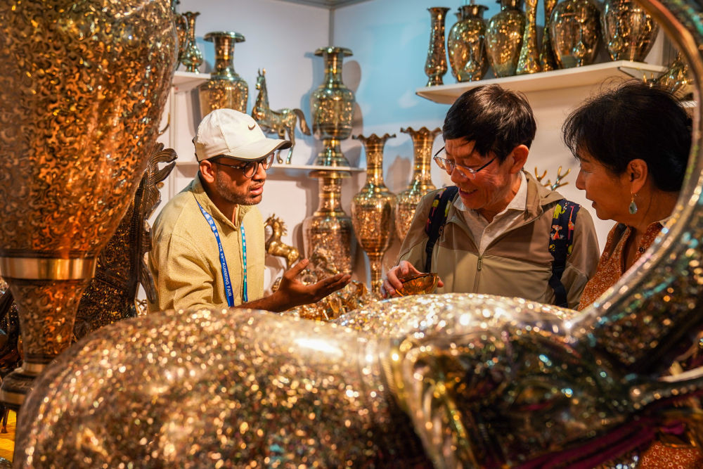 6月20日，顾客在南亚馆巴基斯坦展区选购铜制工艺品。