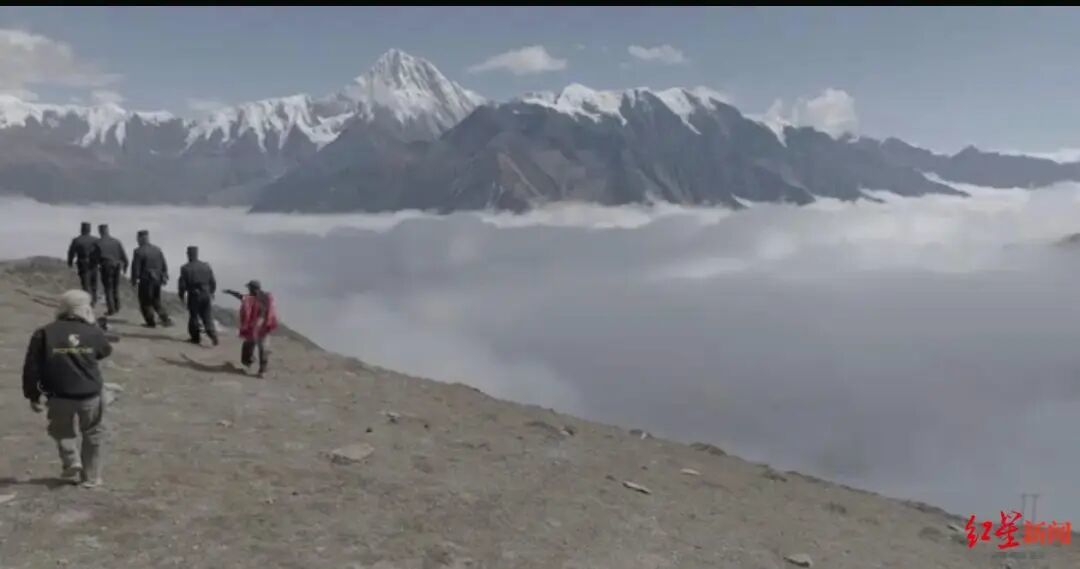 ▲民警在贡嘎大环线子梅垭口巡逻时,身后有女子跳舞