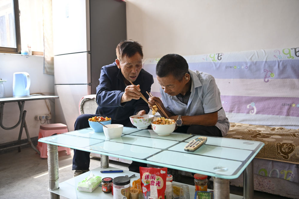 ↑村民桑建平（左）为秦海松夹菜（2025年8月27日摄）。