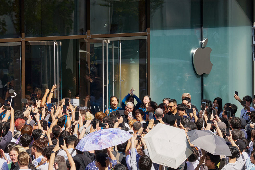 Apple 银座零售店外，Tim Cook 身边围着顾客和团队成员。