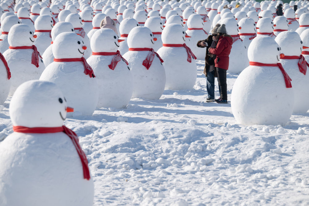 ↑1月4日，在北大荒集团闫家岗农场，游客与雪人拍照。新华社记者 张涛 摄