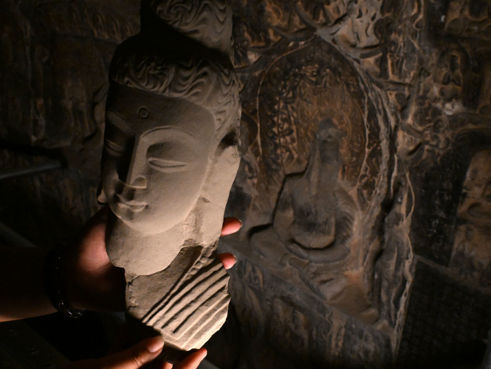 4月10日，龙门石窟研究院工作人员在古阳洞高树龛前查看3D打印佛首模型。