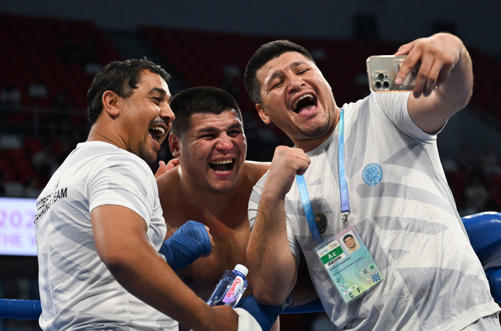 2025年8月14日，在成都世运会自由搏击男子K1 91公斤以上级铜牌赛中，乌兹别克斯坦选手巴拉托夫战胜法国选手库利巴利，获得铜牌。图为巴拉托夫（中）与教练在比赛后自拍庆祝胜利。新华社记者 张博文 摄