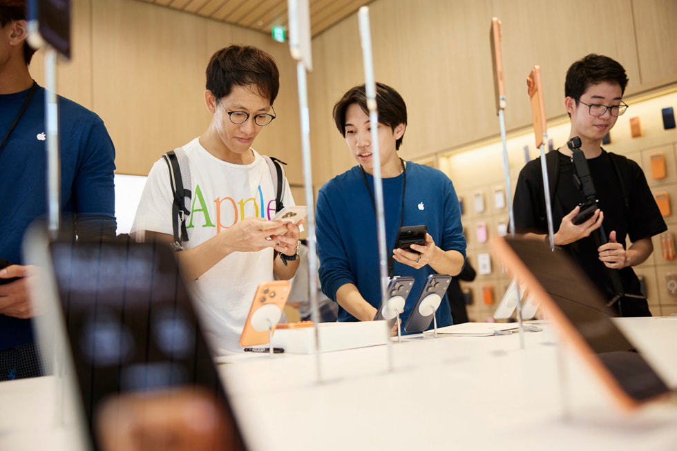Apple 银座零售店内，一名团队成员在为一位手持银色 iPhone 17 Pro 的顾客提供协助。