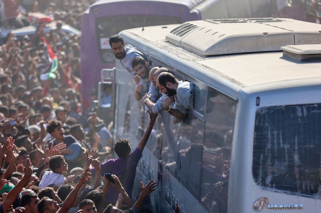 当地时间2025年10月13日,加沙地带南部汗尤尼斯,根据与巴勒斯坦各派达成的加沙停火和人质交换协议,载有从以色列监狱释放的巴勒斯坦人的巴士抵达纳赛尔医院外。视觉中国 图