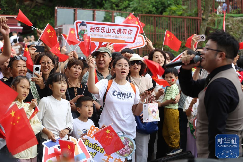 10月1日,游客在四川省乐山市大佛景区佛头广场合唱歌曲《我和我的祖国》。新华社发(李华时摄)