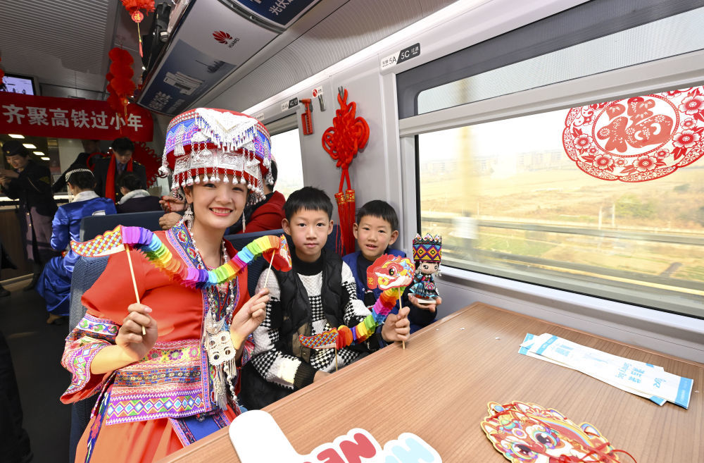 小年來臨之際,，身著土家族服飾的鐵路上海客運段職工與旅客合影,。車隊職工為旅客帶來民族歌舞,、寫福字等活動，讓旅客在旅途中感受濃厚的節(jié)日氛圍,。