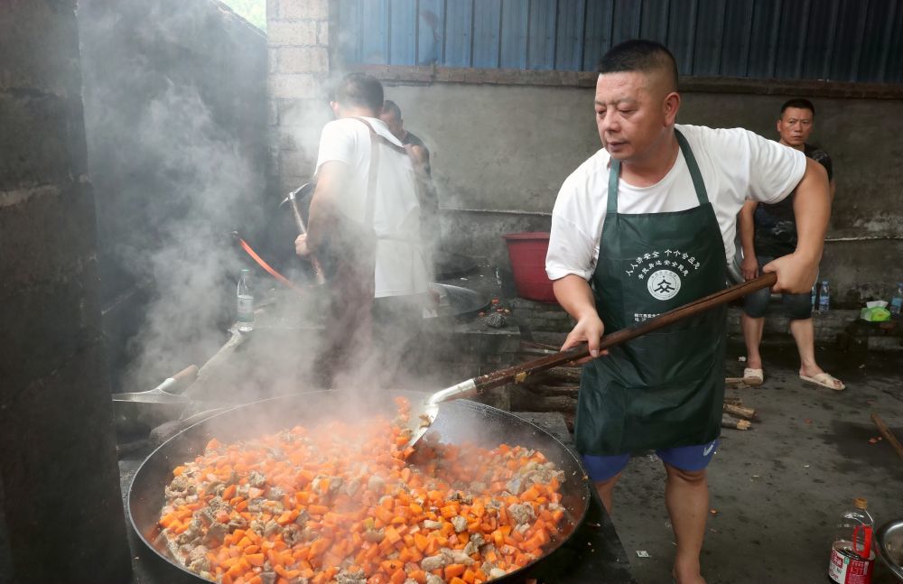 6月29日，在榕江县古州镇口寨社区一后勤伙食保障点，党员阙江勇在炒菜。新华社发（李长华 摄）