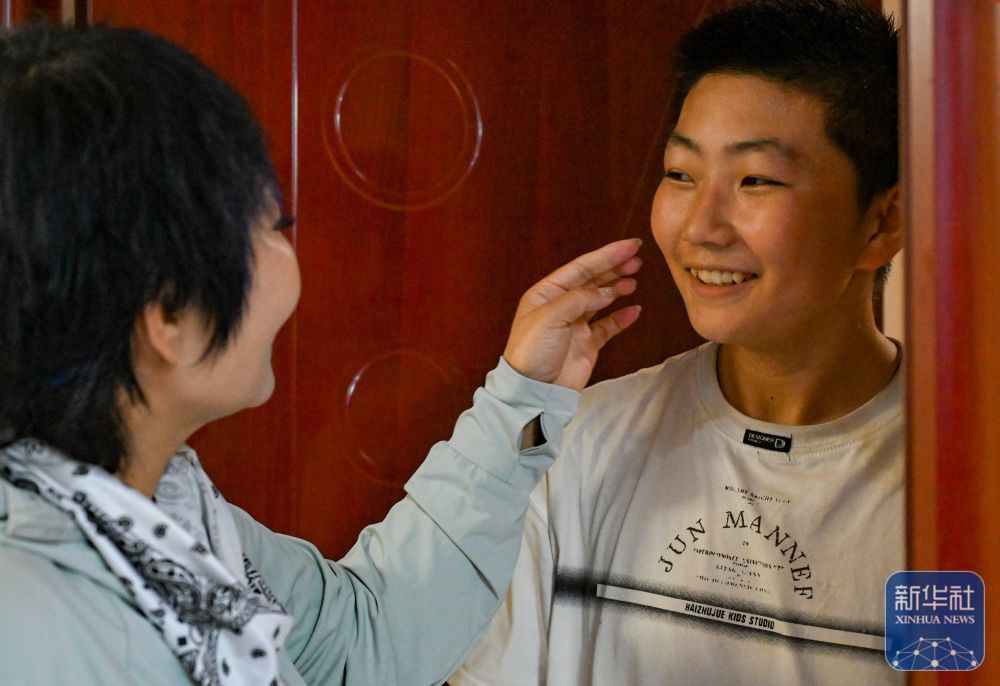 高云(左)在新疆霍尔果斯家中同儿子告别(6月9日摄)。这次运车出国的任务在晚上,她当天无法回家陪伴儿子。