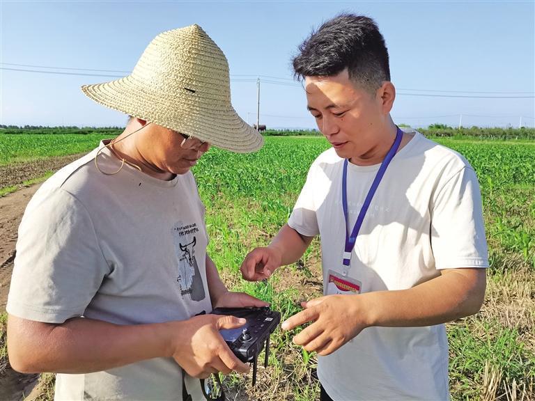 新农人齐昆(右)指导农户使用无人机(资料照片)。 受访者供图