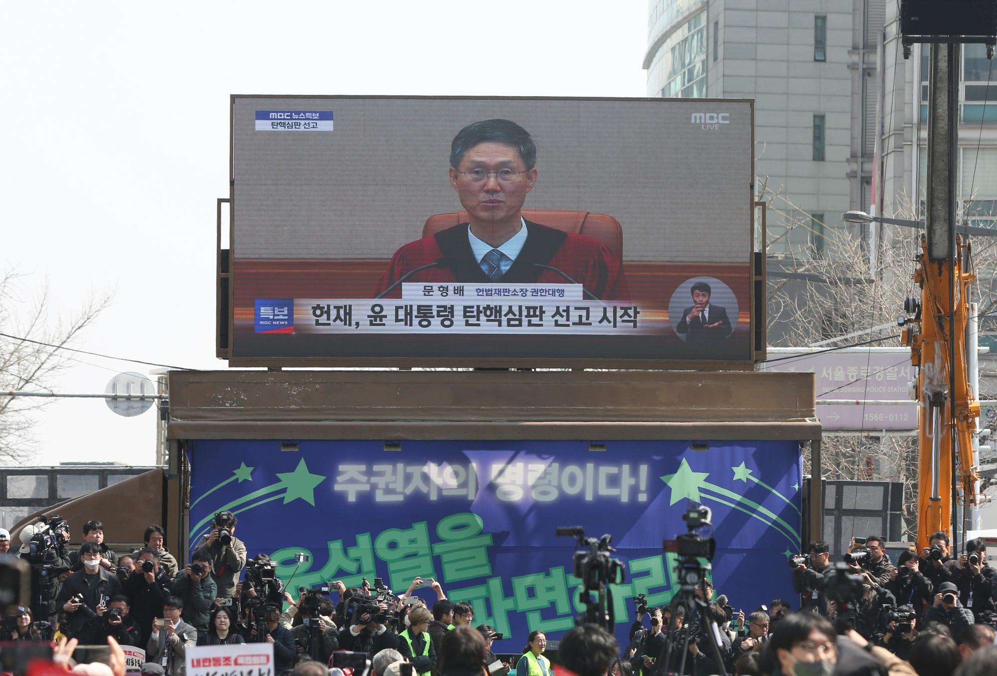 4月4日，民众在韩国首都首尔的韩国宪法法院附近观看尹锡悦弹劾案宣判过程的电视直播。新华社记者姚琪琳摄