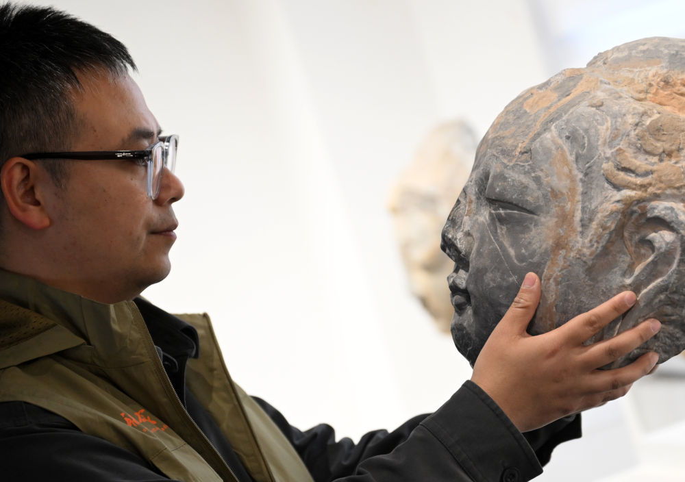 4月10日，龙门石窟研究院工作人员在查看3D打印佛首模型。