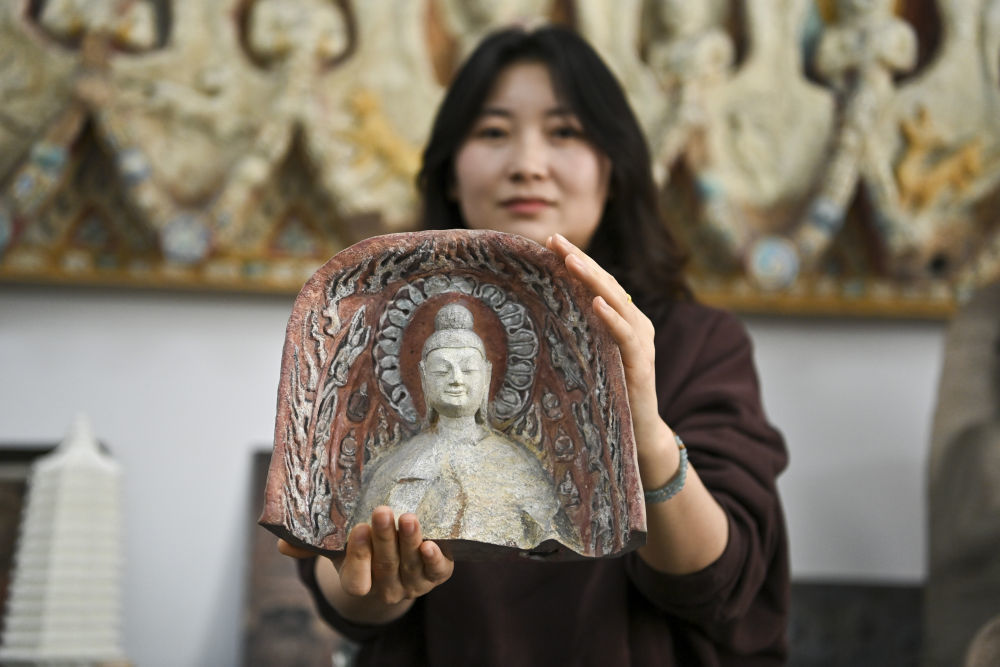 4月16日，在云冈研究院数字化保护中心展厅，工作人员王娜展示一款3D打印佛像模型。