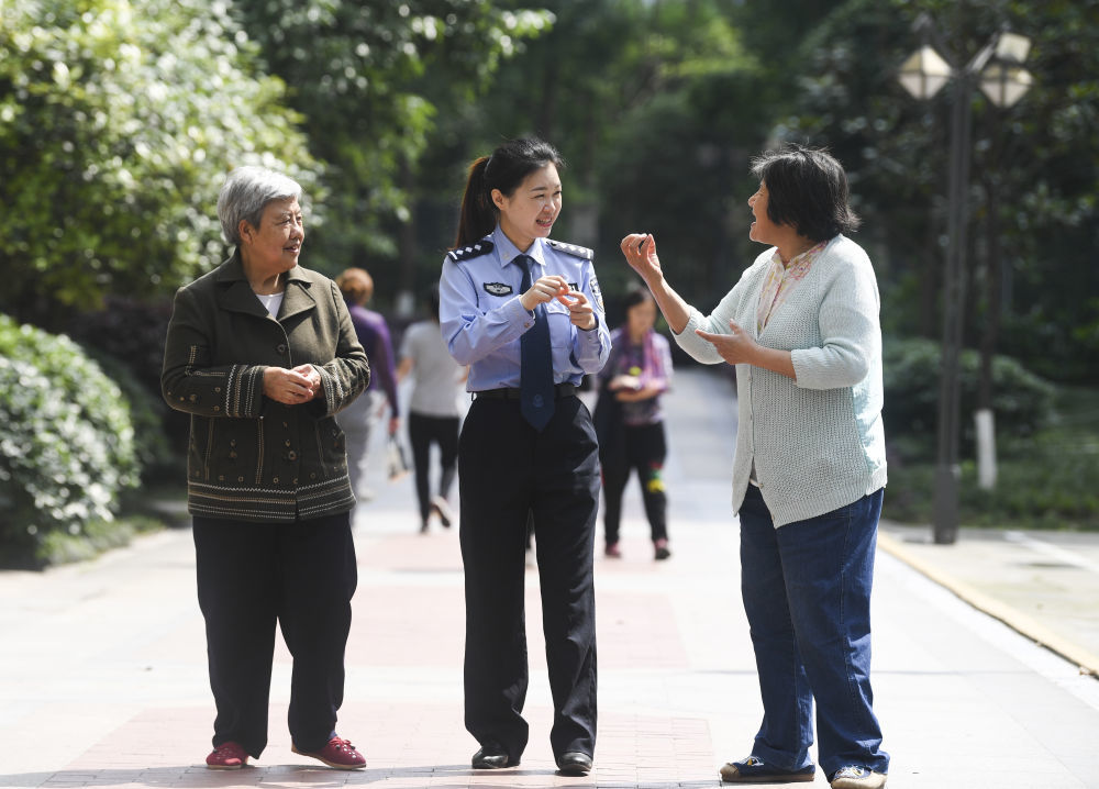 2021年4月27日,重庆市公安局沙坪坝区分局磁器口派出所民警何巧(中)与磁建村社区的聋哑群众交流。何巧用一年多时间自费学会通用手语,把辖区近200名听障居民当成亲人,沟通无声与有声的“双重世界”。