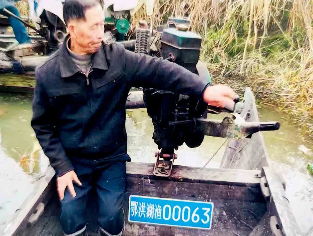 2016年,湖北洪湖市乌林镇,梅连清的父亲上交自家渔船时与渔船合影。图/受访者提供 翻拍/本刊记者 吕雅萱