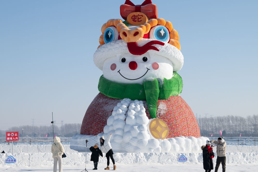 ↑1月4日，在北大荒集团闫家岗农场，游客与雪人合影。新华社记者 张涛 摄