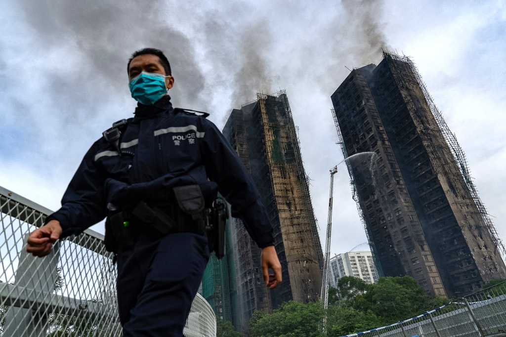 11月27日上午,香港,一名警察走过大埔宏福苑住宅区火灾现场。