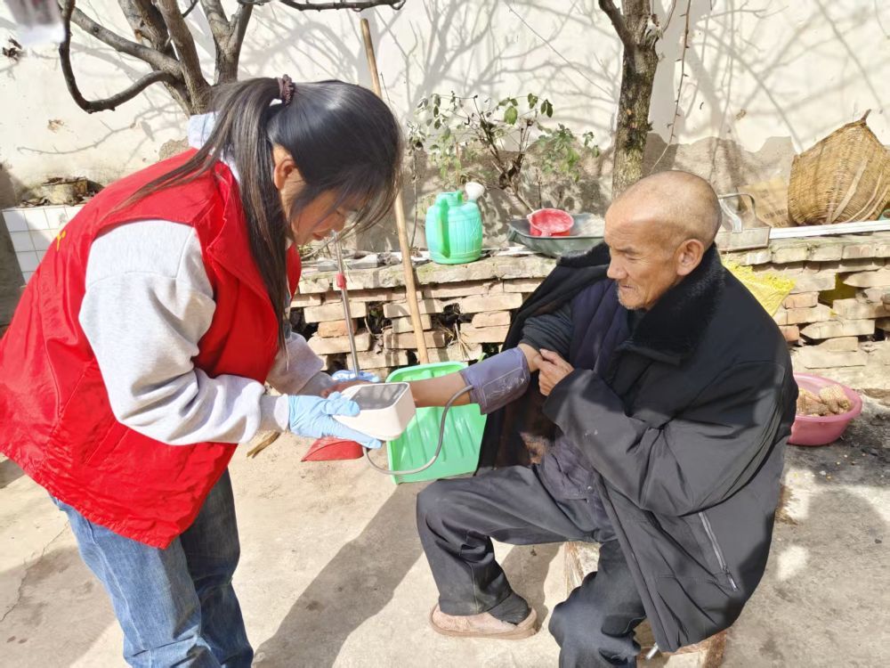 2025年11月，甘肃省陇南市宕昌县益民社会工作服务中心养老护理员赵雪林为南河镇寺卜寨村张尕旦老人测量血压。（李善芳 摄）