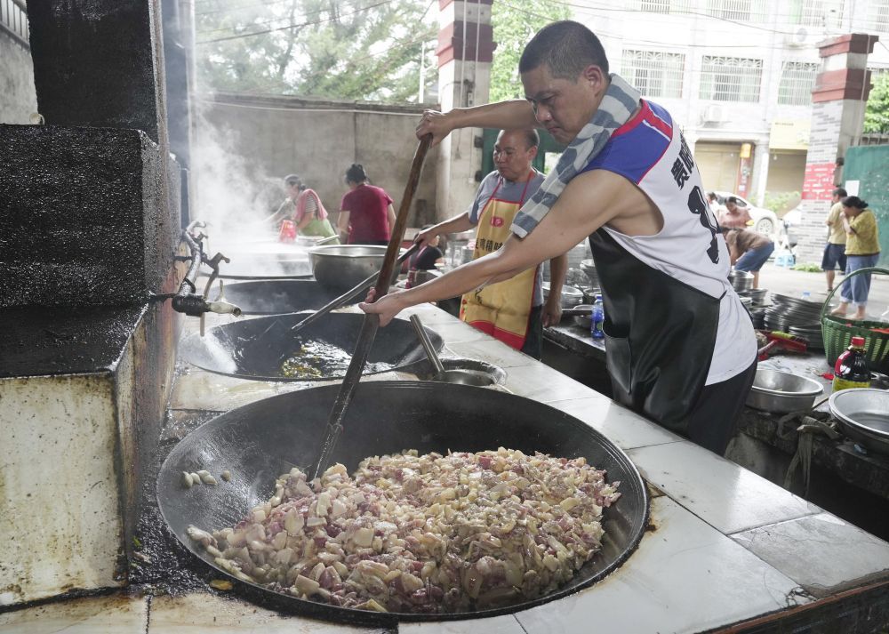 ↑6月26日,村民在忠诚镇一处后勤伙食保障点炒菜。