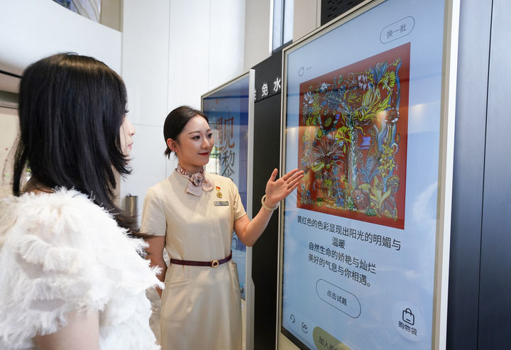 游客（左）在杭州万事利科创中心体验人工智能丝巾设计（2025年4月24日摄）。新华社发