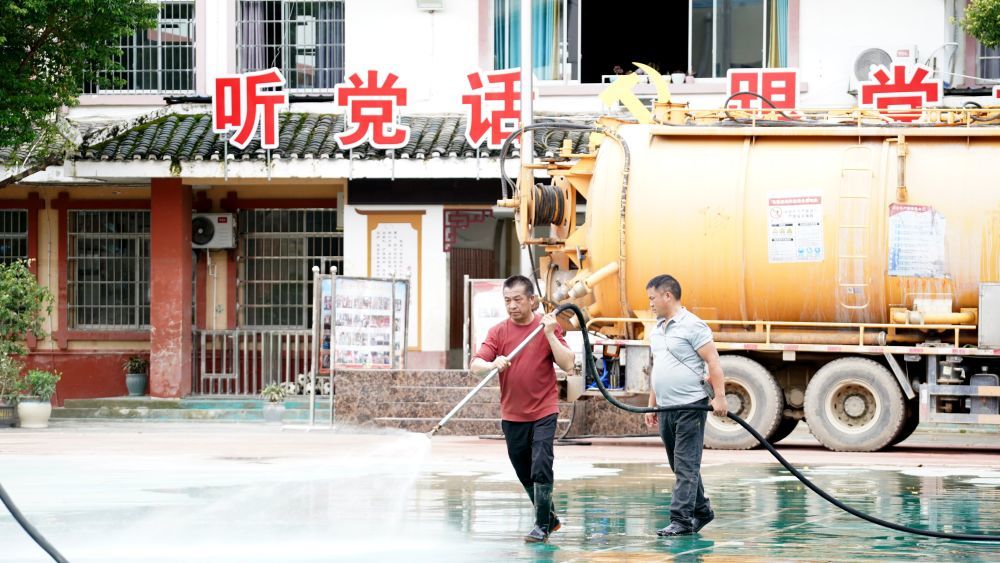 6月29日，党员志愿者在榕江县城清洗校园地面。新华社发（王炳真 摄）