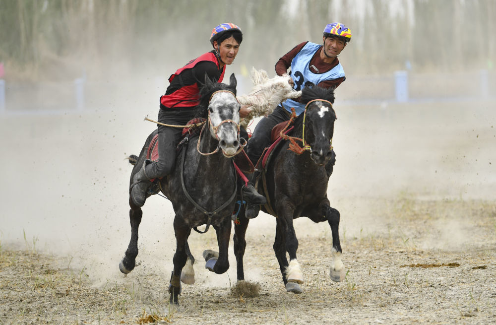4月12日，村民在新疆于田县先拜巴扎镇农牧民运动场参加叼羊比赛。新华社记者 胡虎虎 摄