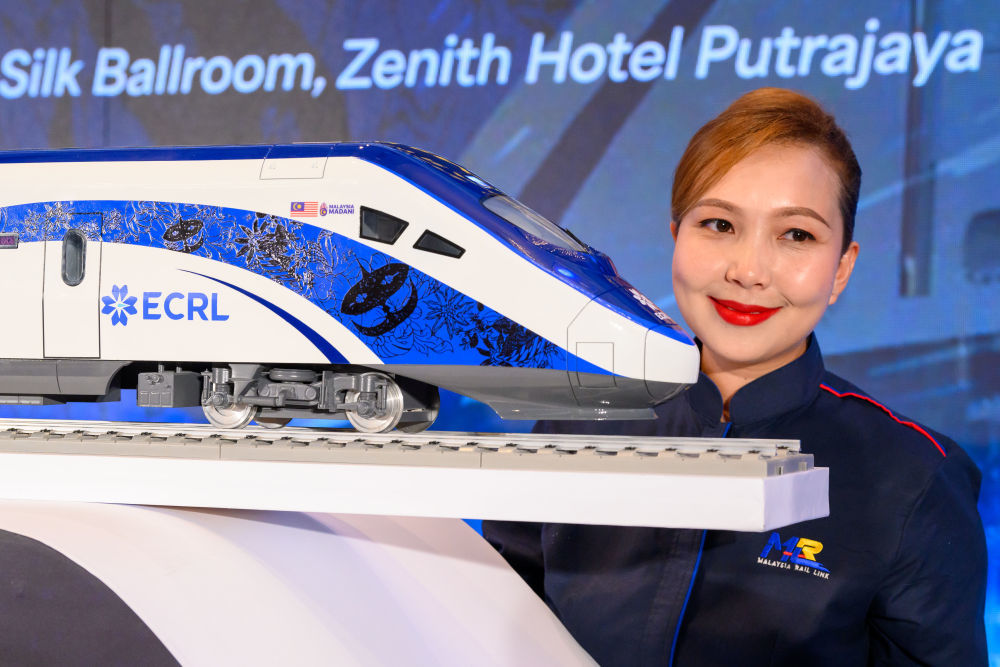 2024年12月18日，在馬來西亞普特拉賈亞,，模特與新的動車組模型合影,。新華社發(fā)（張紋綜攝）