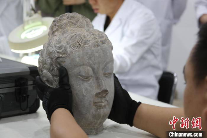5月20日，河南洛阳，龙门石窟研究院工作人员展示已完成修复的唐代佛头。　中新社记者 阚力 摄