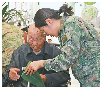 马章锁与志愿者一起包粽子。