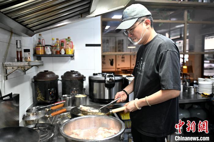 图为陈骏凯正在店内厨房制作菜品。中新网记者 吕明 摄