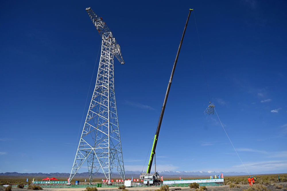 在新疆哈密市伊吾县，哈密—重庆&plusmn;800千伏特高压直流输电工程施工现场，工程建设人员进行铁塔组立作业（2024年7月12日摄）。新华社发（马元 摄）