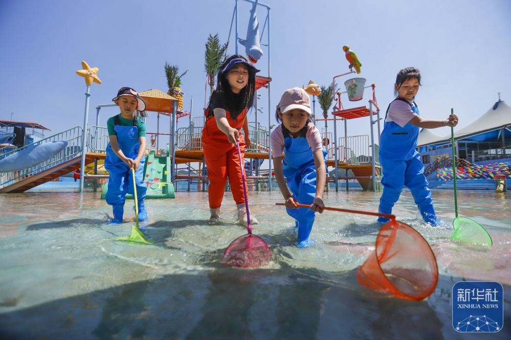 ↑ 5月24日，游客在河北省遵化市南山常乐谷景区水世界参加亲子捞鱼活动。新华社发（刘满仓摄）