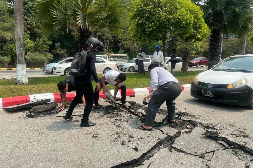 当地时间3月28日,缅甸内比都,在中部发生地震后,驾驶员在受损的道路上清理碎片。