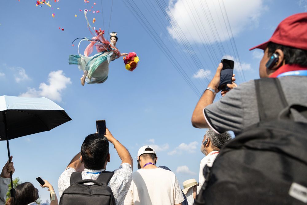 7月26日,上海合作组织媒体智库峰会与会嘉宾在河南开封清明上河园拍摄“大宋飞天秀”。新华社记者 白雪骐 摄