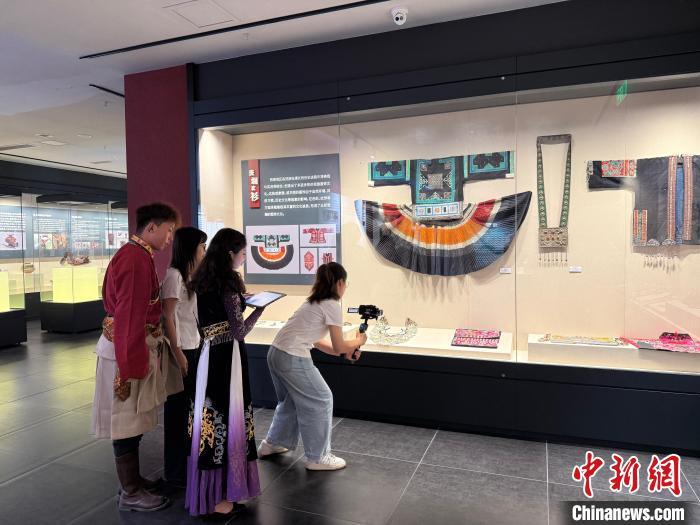 5月15日，迪拉热·阿地力江与同学在西南民族大学民族博物馆拍摄民族服饰。　中新网记者 贺劭清 摄