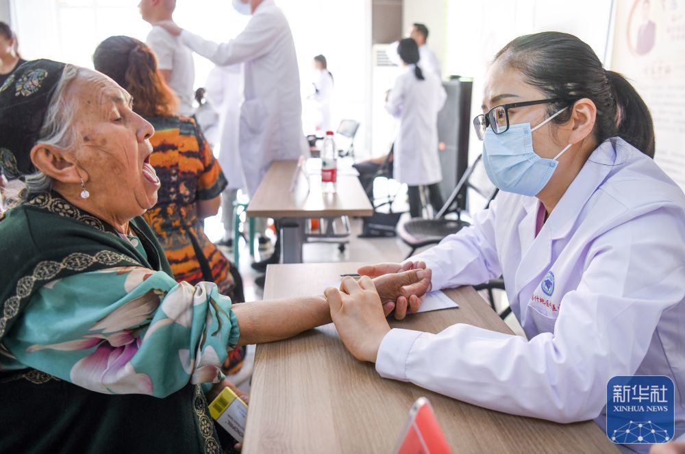 ↑ 在新疆喀什市夏马勒巴格镇团结小区，来自山东中医药大学第二附属医院的援疆医生李荣华（右）为居民义诊（2023年9月16日摄）。新华社记者 王菲 摄