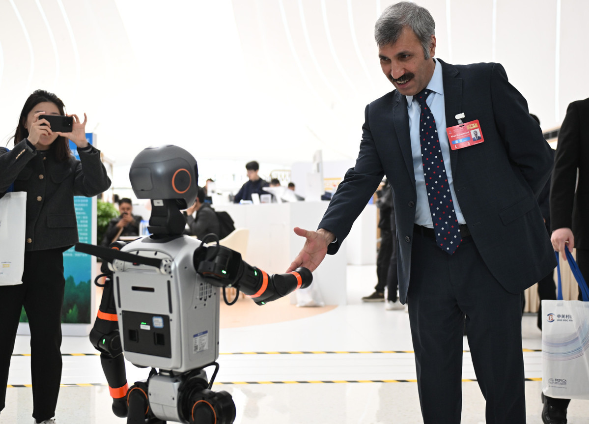 3月27日，与会嘉宾与一款加速T1机器人握手。（图片来源：新华社）