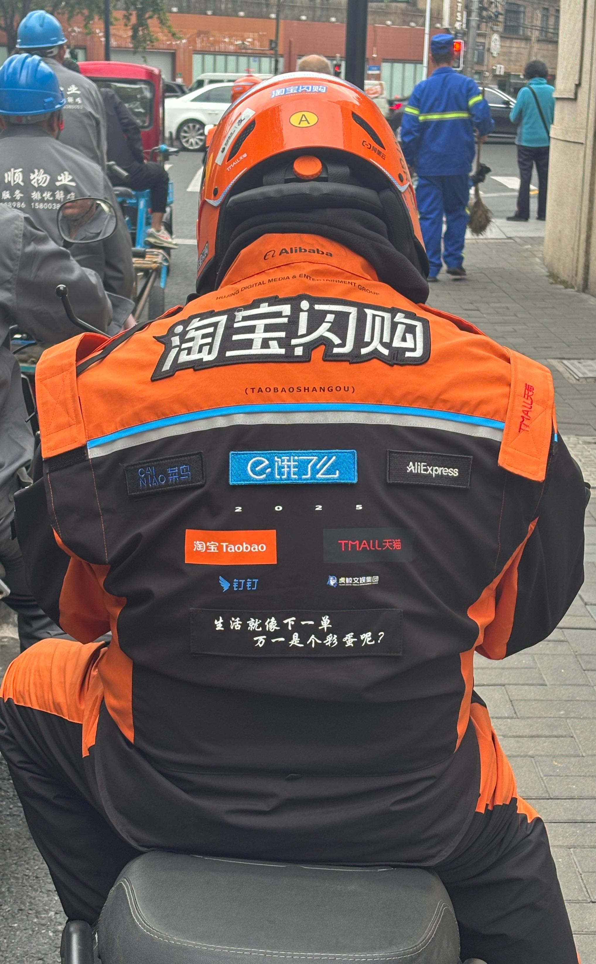 饿了么外卖小哥换上的淘宝闪购橙黑色工作服,背面显示出众多logo。