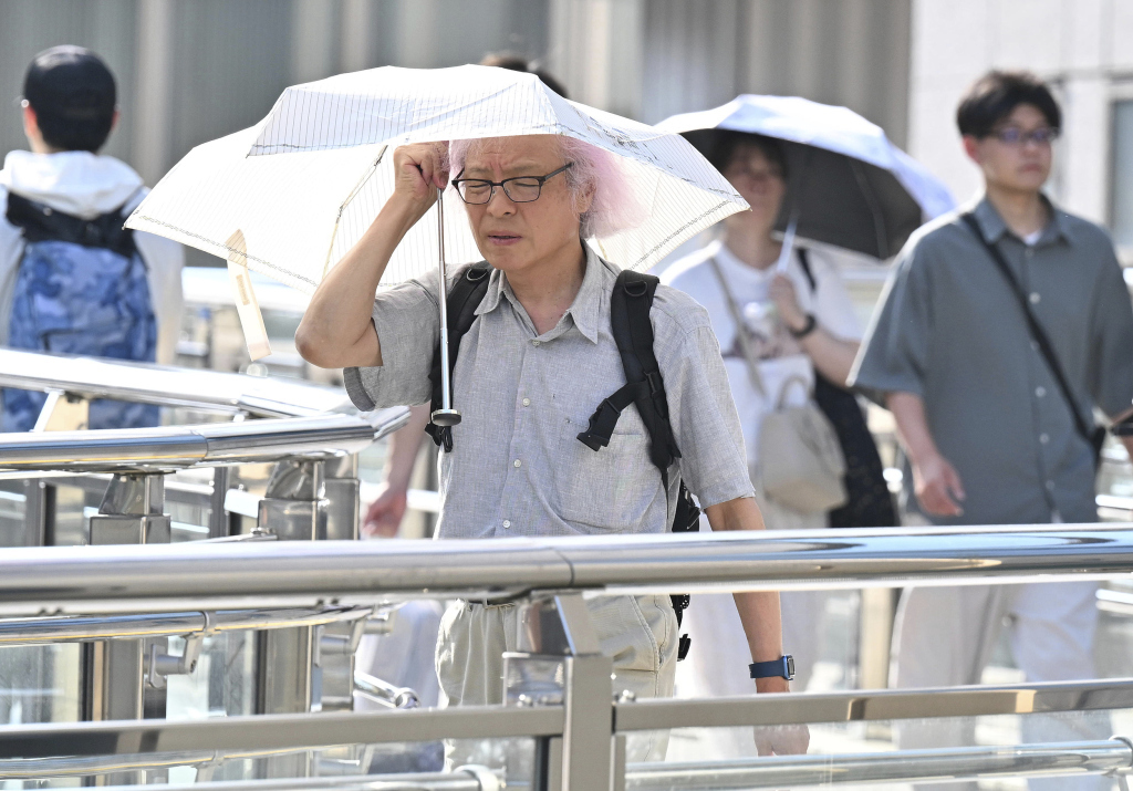 当地时间2025年8月5日，日本东京八王子市，民众在酷热中出行。视觉中国 图