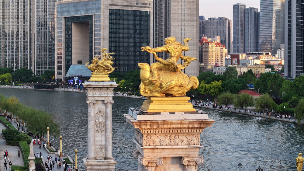 海河从天津城中蜿蜒而过，其上架设的众多桥梁链接着城市的历史与未来，也是展现天津文化海纳百川特质的一扇窗口。其中的北安桥历史最早可追溯到1939年，其设计借鉴了巴黎塞纳河上的亚历山大三世桥，桥头雕塑又吸取了中国传统文化元素。这是2024年5月1日拍摄的北安桥桥头柱及青龙、玄武雕像（无人机照片）。