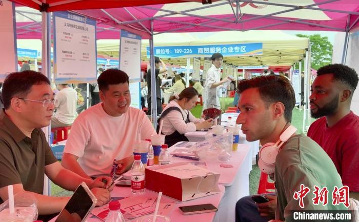 4月22日，留学生维克托(右一)和丁凯(右二)在招聘会现场了解岗位详情。刘子琳 摄