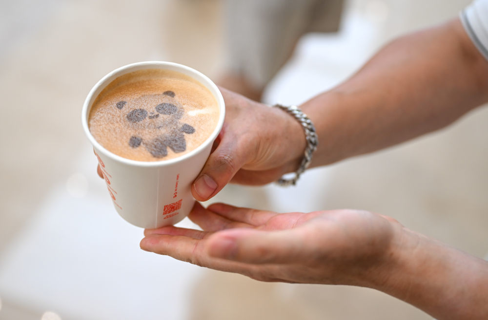 8月4日，一名媒体记者在成都世运会主媒体中心展示由咖啡机器人制作的带有吉祥物“蜀宝”图案的饮品。新华社记者 贝赫 摄