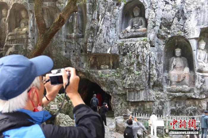 12月1日，游客在飞来峰造像前拍照留念。孙琳茹　摄