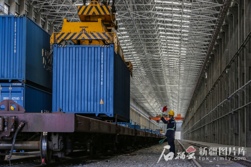 6月24日，工作人员在阿拉山口站中欧（中亚）班列换装区指挥行车吊装集装箱。